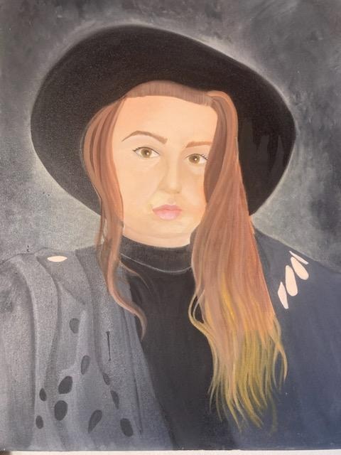 Portrait of a person with long hair wearing a wide-brimmed black hat